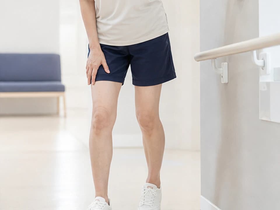 무릎 불안정감으로 벽을 짚으며 균형을 잡는 모습